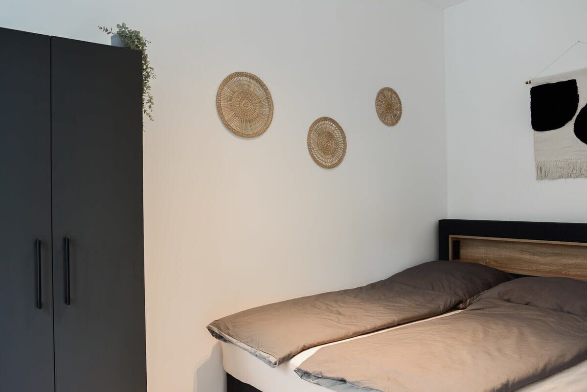 A bedroom with a bed, a wardrobe, and three wall-mounted circular woven decorations.
