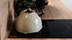 Een keuken met een waterkoker, een koffiezetapparaat en een zwart inductiekooktoestel.