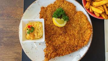 Un plato con milanesa, papas fritas y una ensalada de macarrones.