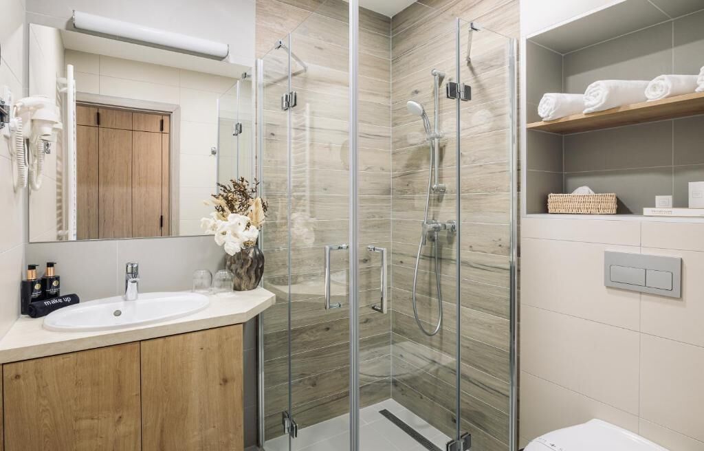 Un baño moderno con cabina de ducha de vidrio, tocador con lavabo y espejo.