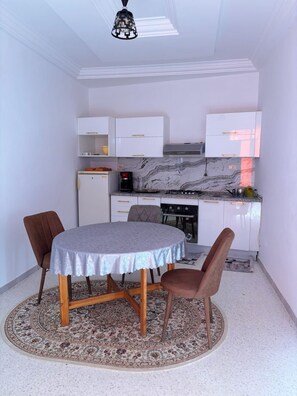 Una cocina compacta con armarios blancos, una estufa a gas y una cafetera.