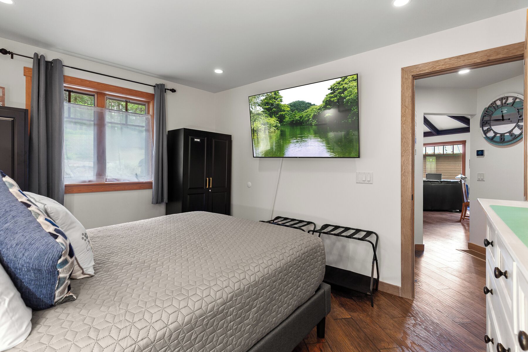 A bedroom with a bed, a TV, a wardrobe, and a clock on the wall.