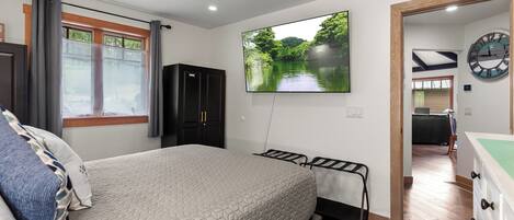 A bedroom with a bed, a TV, a wardrobe, and a clock on the wall.