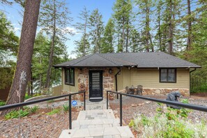 A lodge with a stone facade, a black door, and a small porch with outdoor seating. - New Listing! Lakeside Retreat | Fire Pit | Deck with Lake View (Blanchard)