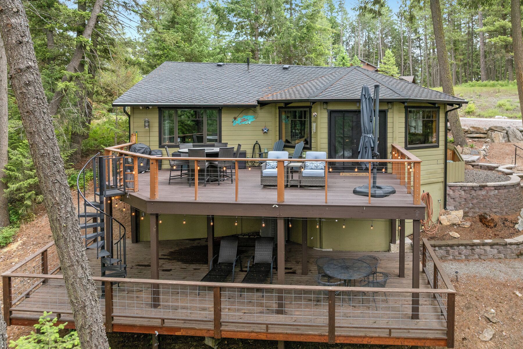 Ein zweistöckiges Haus mit Terrasse, Sitzgelegenheiten im Freien und einer überdachten Veranda.