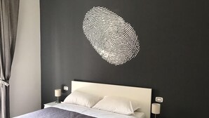 Un dormitorio moderno con cama, mesitas de noche y una original obra de arte en la pared con forma de huella dactilar.