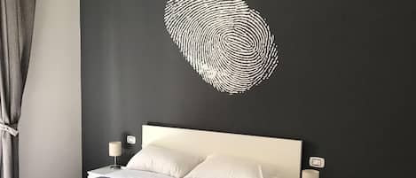 Ein modernes Schlafzimmer mit einem Bett, Nachttischen und einer Wandkunst mit Fingerabdruck-Motiv.