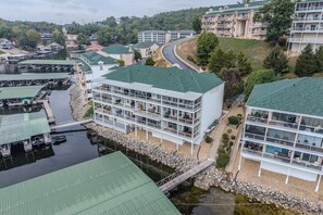 Ein mehrstöckiges Hotel mit Gründach, einem Steg mit Booten und einem Fluss.