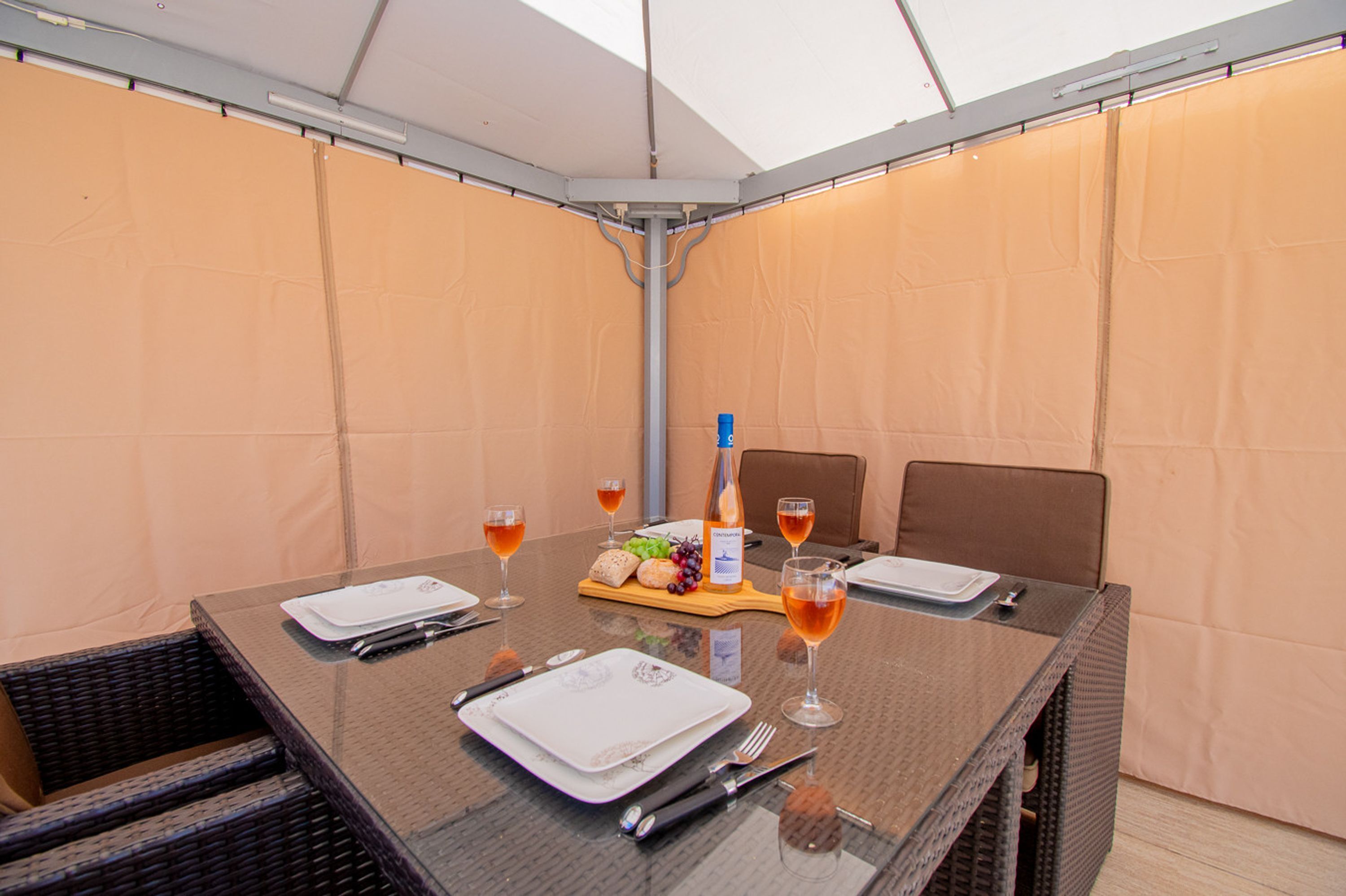 Een gedekte tafel voor twee met wijnglazen, borden, bestek en een broodmand.