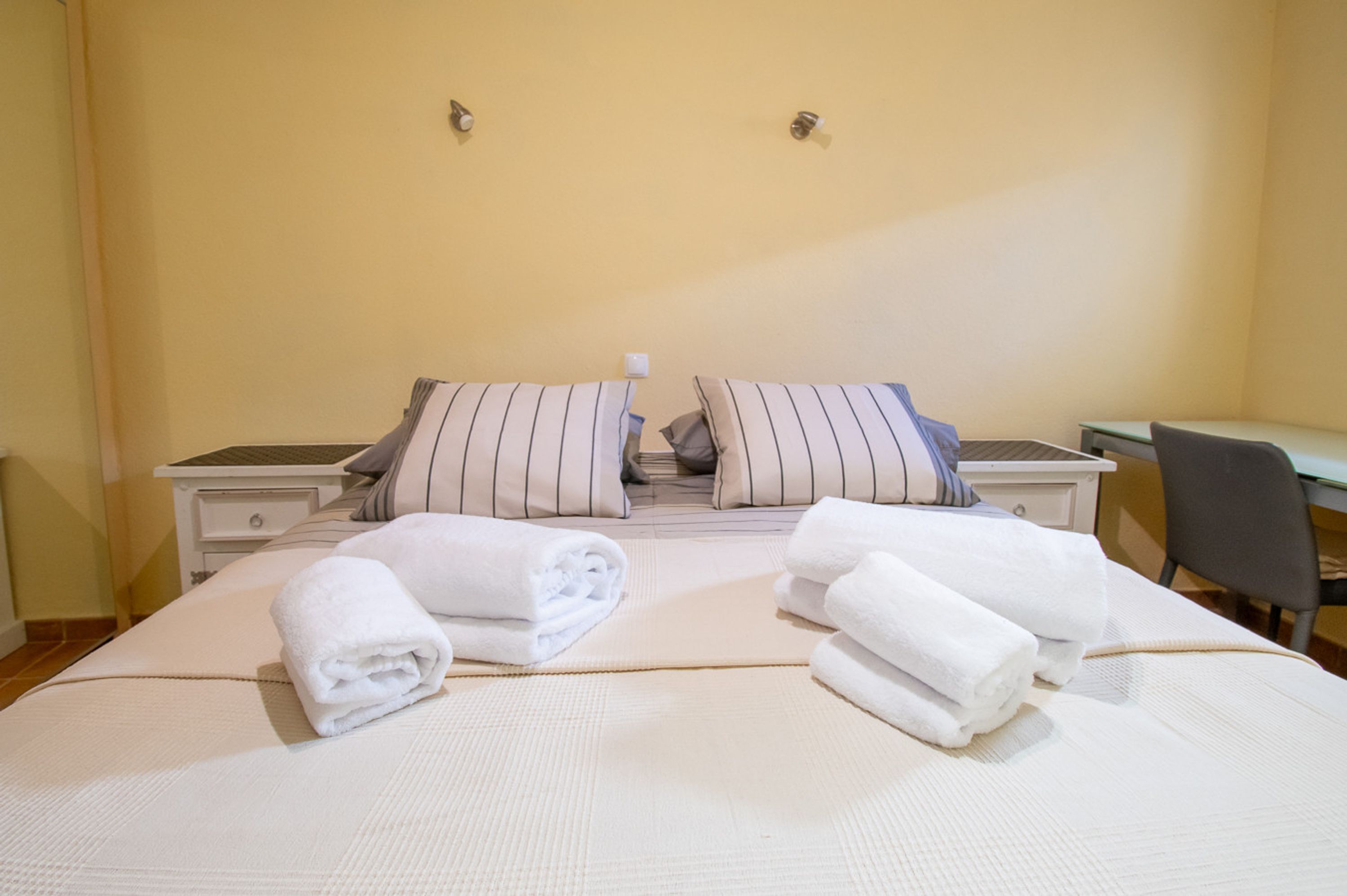 A hotel room with a bed, two bedside tables, a chair, and a desk.