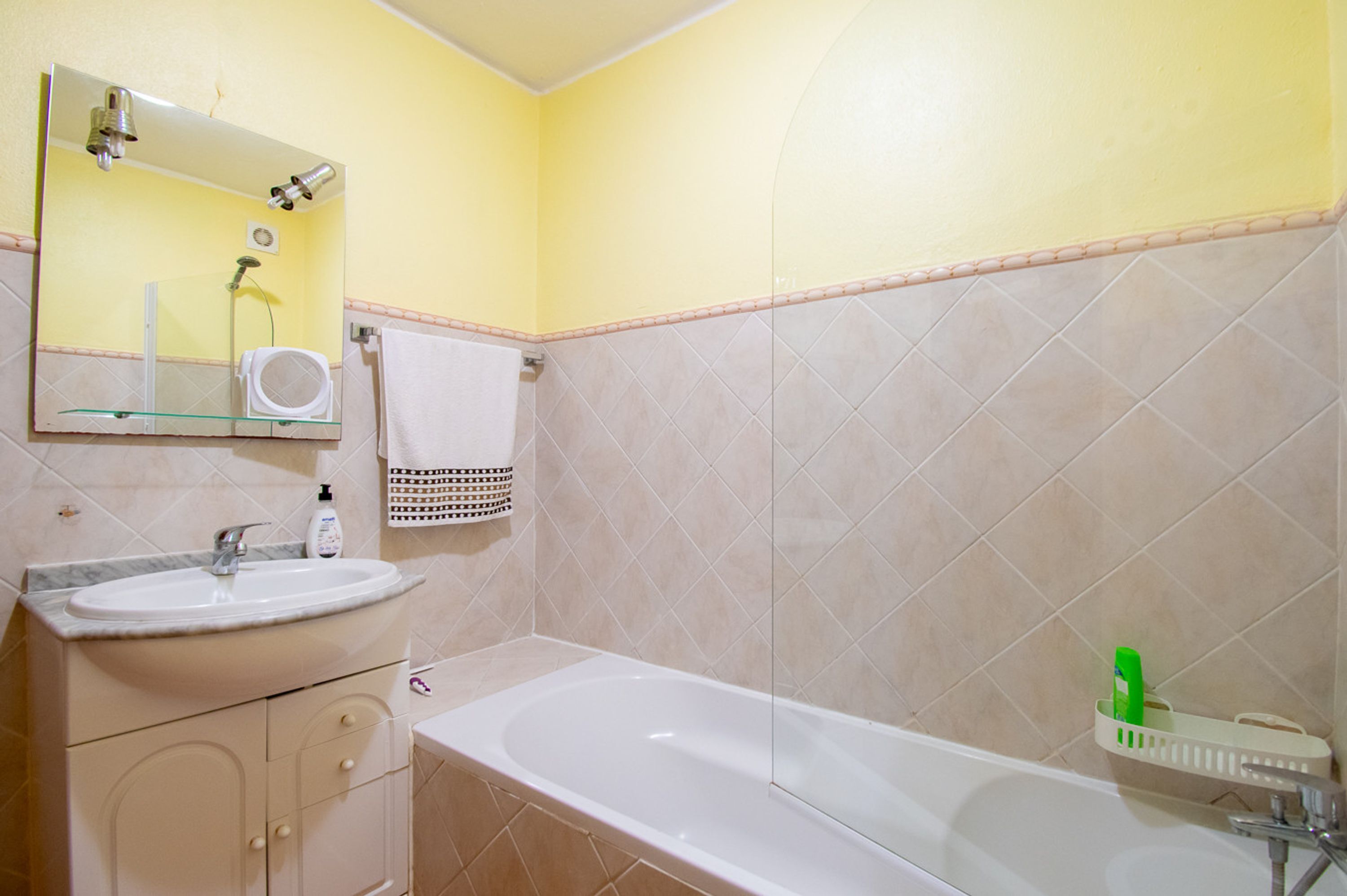 Un baño con lavamanos, espejo y bañera.