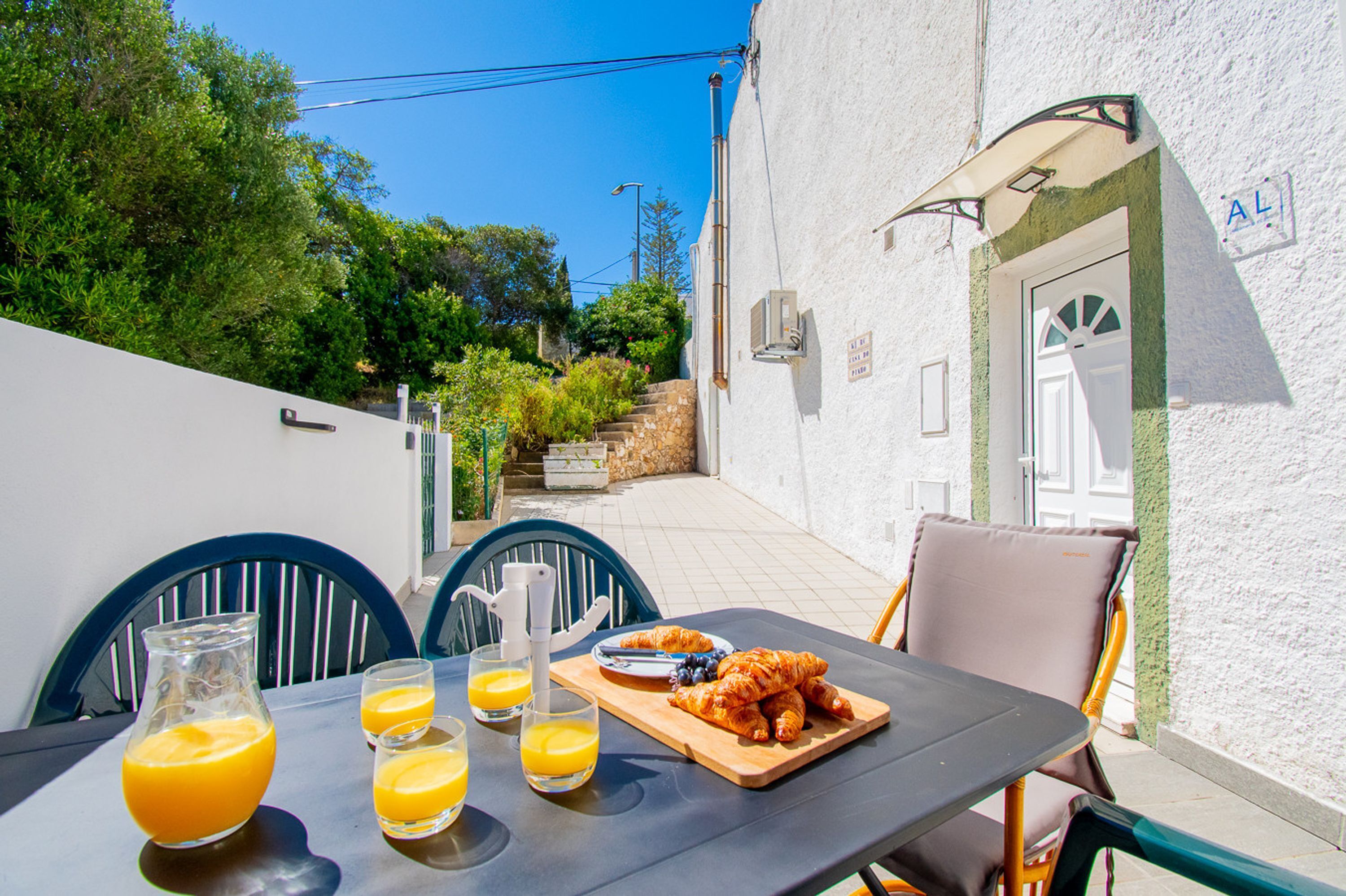 Une table avec des aliments pour le petit-déjeuner et une vue sur un bâtiment blanc, sur lequel on peut voir une enseigne avec les lettres « AL ».