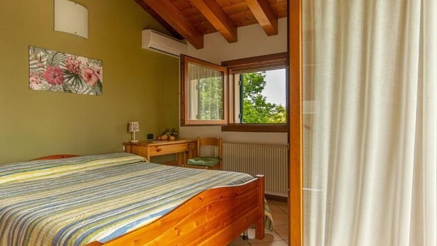 Ein Schlafzimmer mit Bett, Schreibtisch, Stuhl, Fenster mit Blick und Klimaanlage.