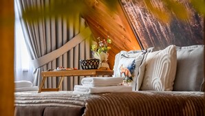 A cozy bedroom with a bed, pillows, a bedside table with a vase of flowers, and a wooden headboard. - Świdrowa Chata Jacuzzi & Sauna (Zakopane)