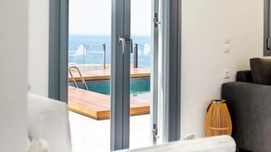 Habitación con un amplio ventanal corredera que da a un espacio exterior con piscina y vistas al mar.