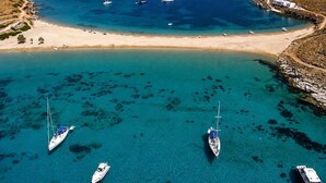 Una zona costera con aguas turquesas cristalinas, embarcaciones y una playa de arena.