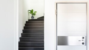 Una escalera con una planta en maceta, que conduce a una puerta con pomo metálico y cerradura.