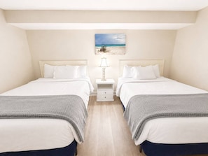 A room with two beds, a nightstand with a lamp, and a beach-themed picture on the wall. - BEACH DAZE GETAWAY/PRIME LOCATION (Myrtle Beach)