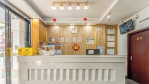Ein Hotelrezeptionsschalter mit einer Holzwand, einer Uhr und verschiedenen Schildern und Zertifikaten.