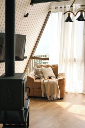 A cozy room with a sofa, a fireplace, and a balcony view.