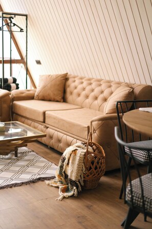 A cozy room with a tufted sofa, a round table, a wicker basket, and a patterned rug.