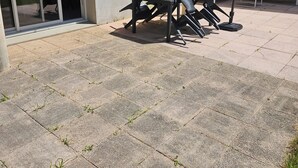 An outdoor patio with a table and chairs, a covered bench, and a sliding glass door. - Apartment 10 minutes walk from the beach first floor with terrace (Clairvaux-les-Lacs)