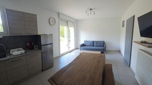 A modern kitchen with a dining table, a sofa, and a TV. - Apartment 10 minutes walk from the beach first floor with terrace (Clairvaux-les-Lacs)