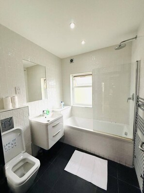A bathroom with a toilet, sink, vanity, bathtub, and a shower area. - Amazing one bedroom flat in London city (Greater London)