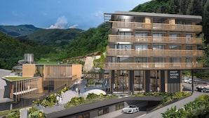 A modern hotel with multiple balconies, a central courtyard, and a view of the surrounding mountains.