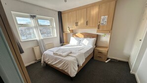 Ein Schlafzimmer mit Bett, Holzschrank, Nachttisch und einem Fenster mit Blick.