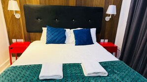 A neatly made bed with a green patterned bedspread, two pillows, and two folded towels. - Specious one bedroom flat in Whitechapel (Greater London)