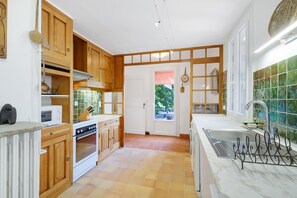 Una cucina con mobili in legno, un piano cottura bianco, un lavello con portariviste in metallo e una finestra vista verde.