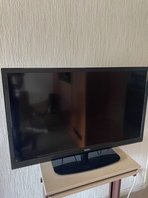 A flat-screen TV on a stand with a white textured wall behind it. - Swiss border 10 minutes from downtown Geneva 50m from tramway (Gaillard)