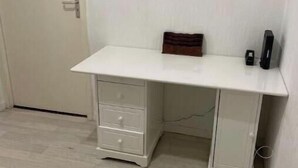 Ett vitt skrivbord med lådor, en liten trälåda och ett svart föremål på skrivbordet.