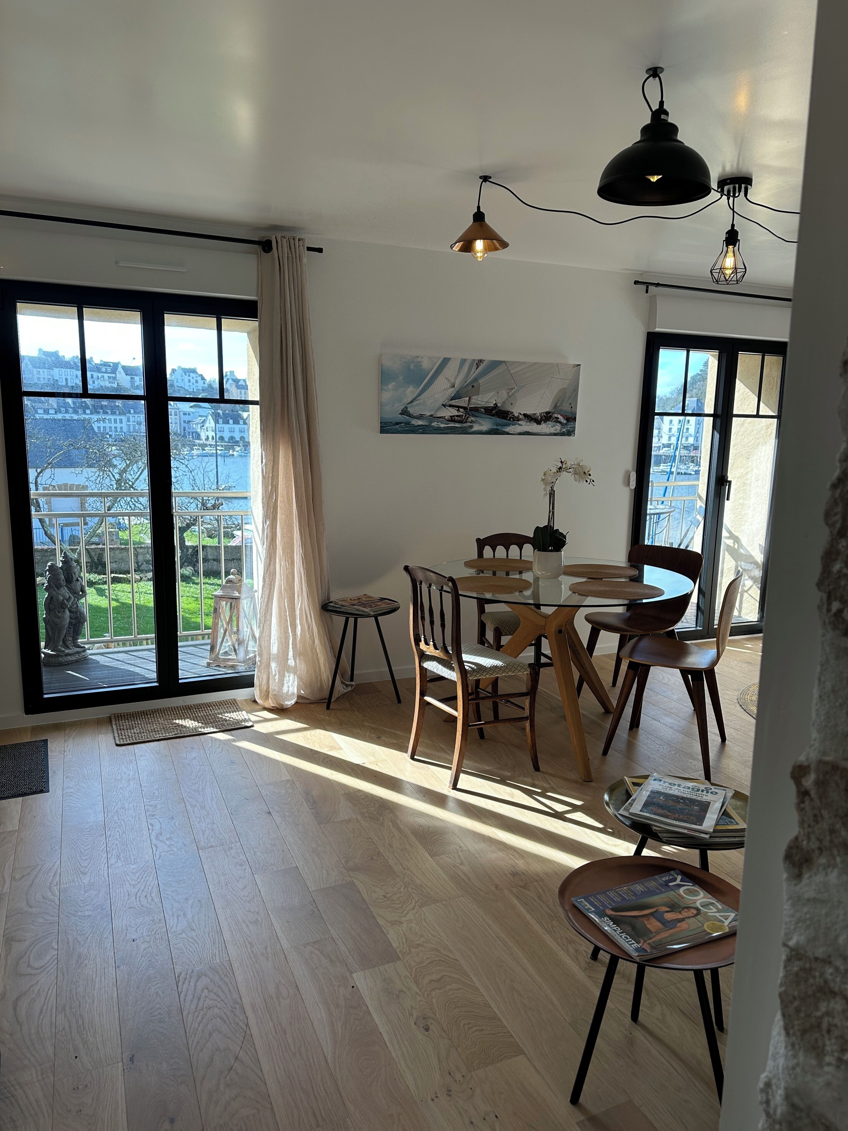 Un comedor con vista al mar, suelo de madera y un cuadro en la pared.