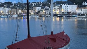 A boat docked at a harbor with buildings in the background. - Port & sea view - Elegant apartment for 2 in Audierne - L'Oasis sur mer (PLOUHINEC)