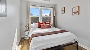 A bedroom with a bed, a window, a bedside table, and a lamp. - Stay Together but with  Privacy of Two Fully Equipped Apartments (Windsor)