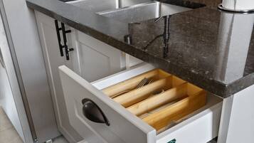 Een keuken met een roestvrijstalen spoelbak, een zwart aanrecht en witte kastjes.