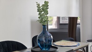 A modern dining area with a wooden table, black chairs, a blue vase with green plants, and a woven placemat. - Stay Together but with  Privacy of Two Fully Equipped Apartments (Windsor)