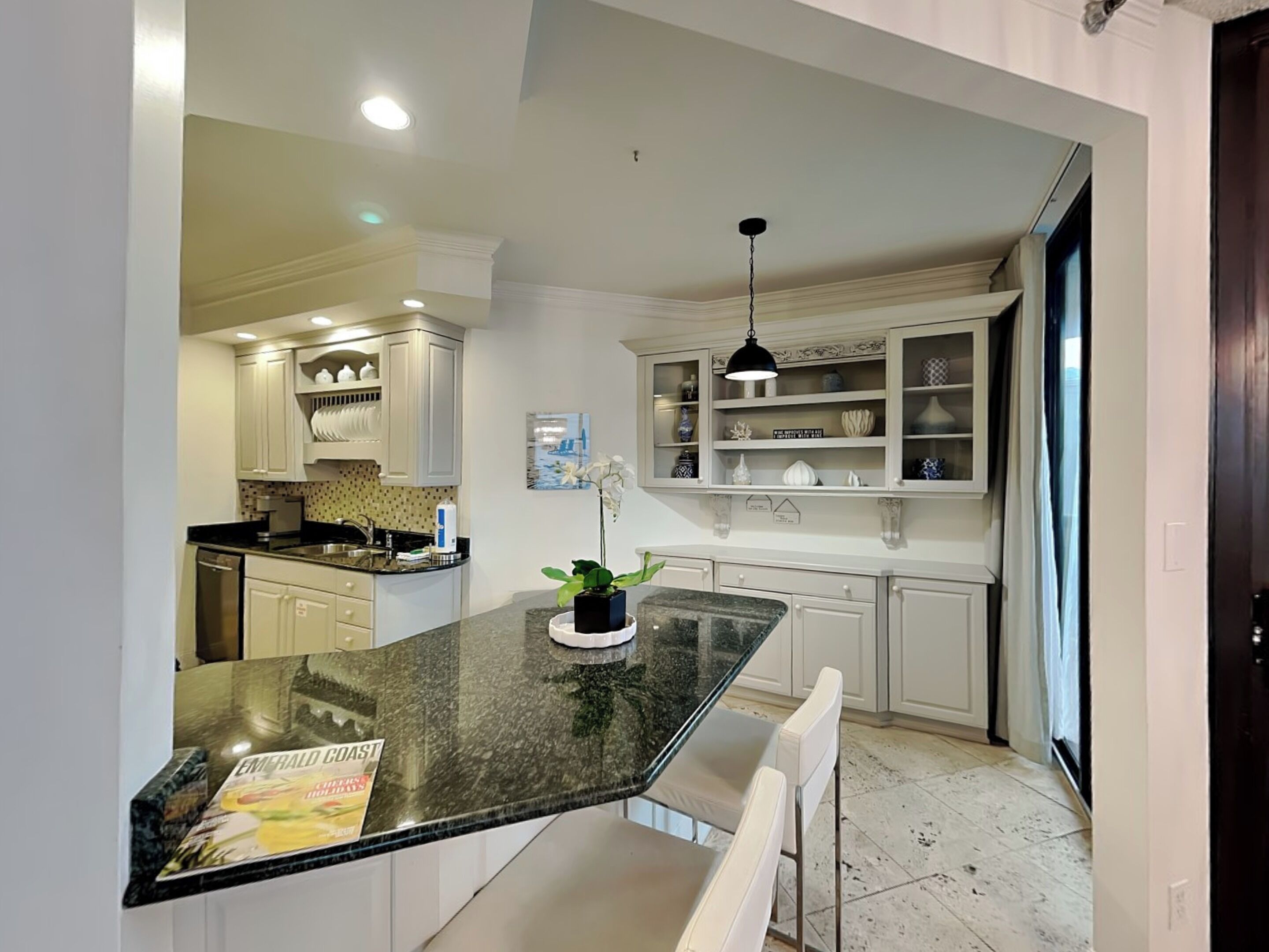 A kitchen with white cabinets, a granite countertop, and a pendant light.