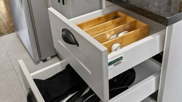 A kitchen with a black countertop, a sink, and a drawer with utensils.