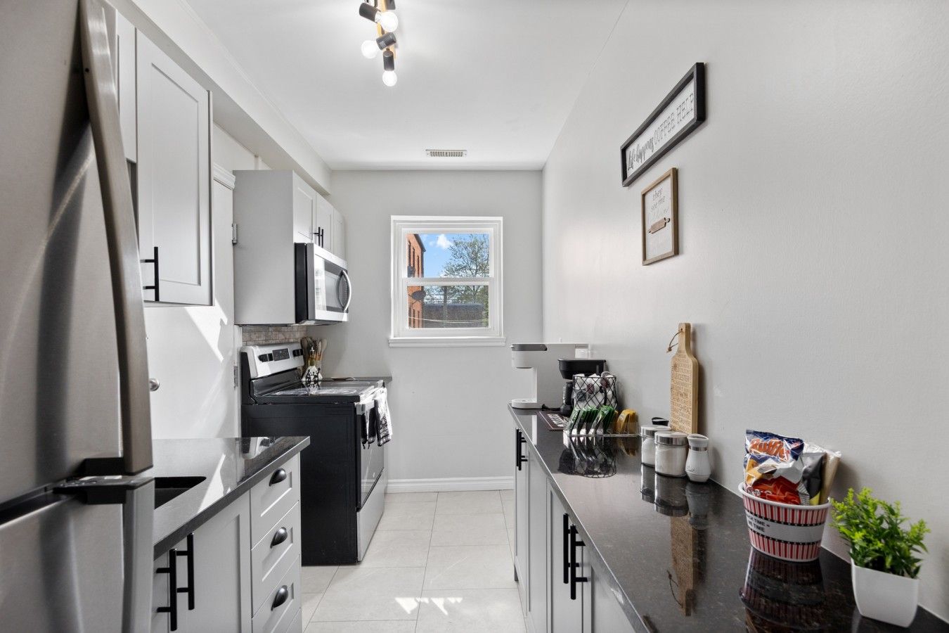 A modern kitchen with stainless steel appliances, a window with a view, and a countertop with kitchen utensils.