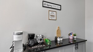 Uma bancada de cozinha com uma cafeteira Keurig, um moedor de café e uma placa com tema de café.
