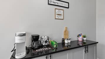 A kitchen counter with a Keurig coffee maker, a coffee grinder, and a coffee-themed sign.