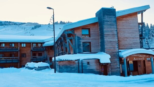Ein Holzhaus mit Balkon und einem Schild, auf dem 'Accueil' steht.