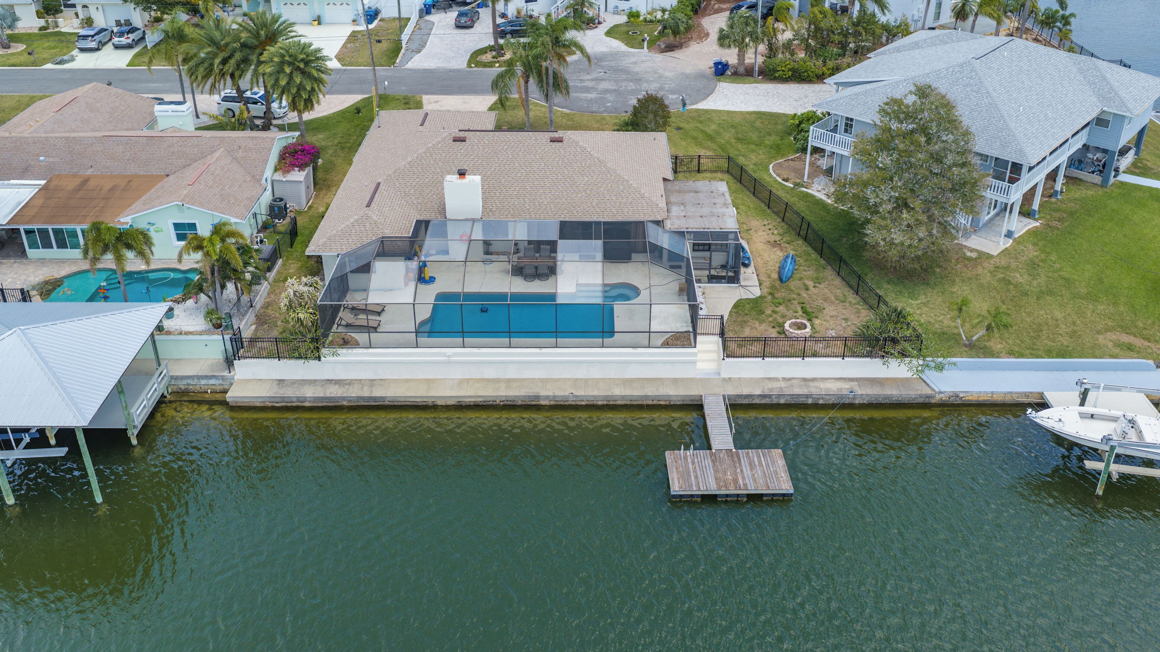 A residential property with a swimming pool, dock, and a view of the water.