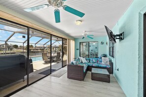 Eine überdachte Terrasse mit Pool, Gartenmöbeln und Deckenventilator.