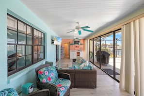 Ein überdachter Patio-Bereich mit Korbmöbeln, einem Deckenventilator und Blick ins Freie.