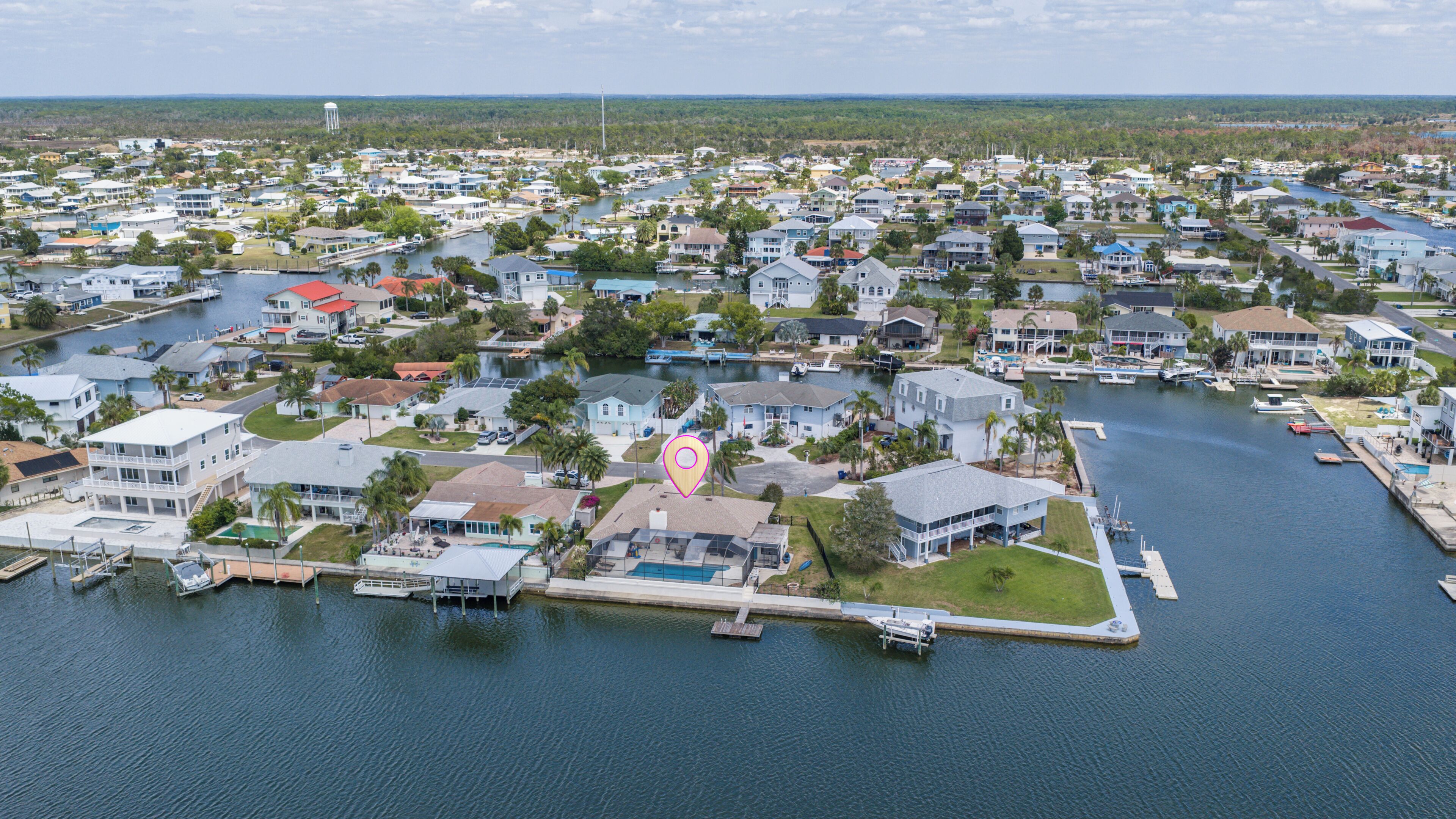 An aerial view of a residential area with houses, a marina, and a body of water.