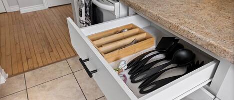 A kitchen with a white stove, a drawer with wooden utensils, and a granite countertop.